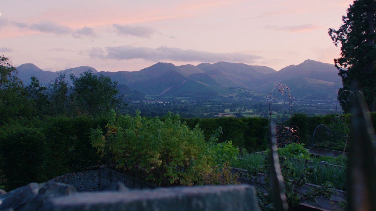 Stunning view from Underscar overlooking Keswick, Derwentwater, and Catbells under candy floss skies at sunset, with lush greenery in the foreground, inspiring adventures like guided walks in the Lake District.